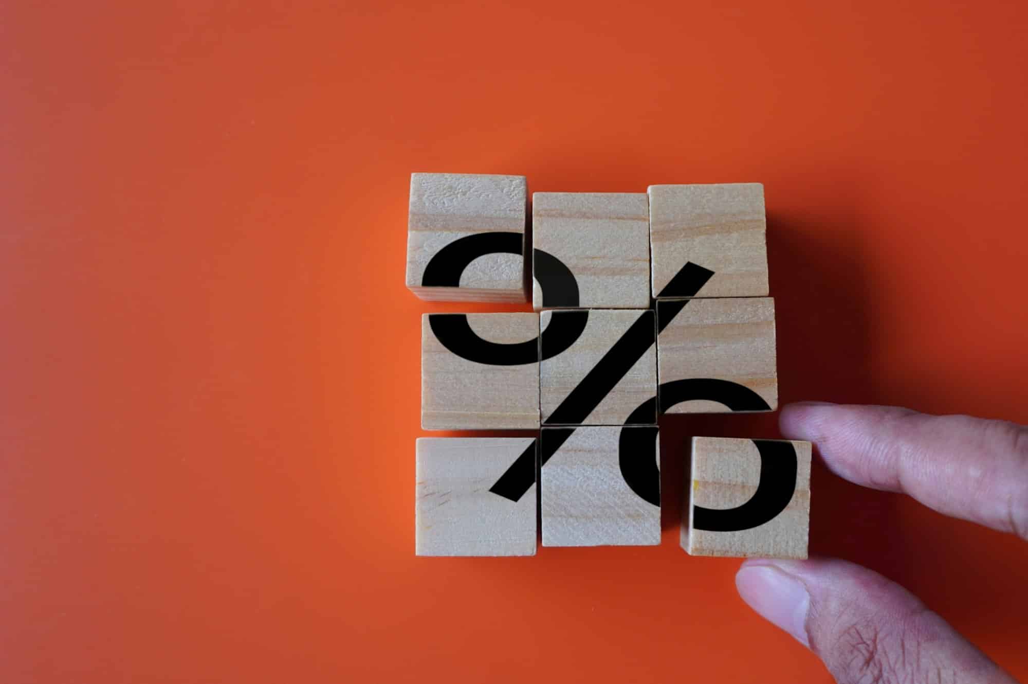 Hand arrange wooden cubes with percentage sign.