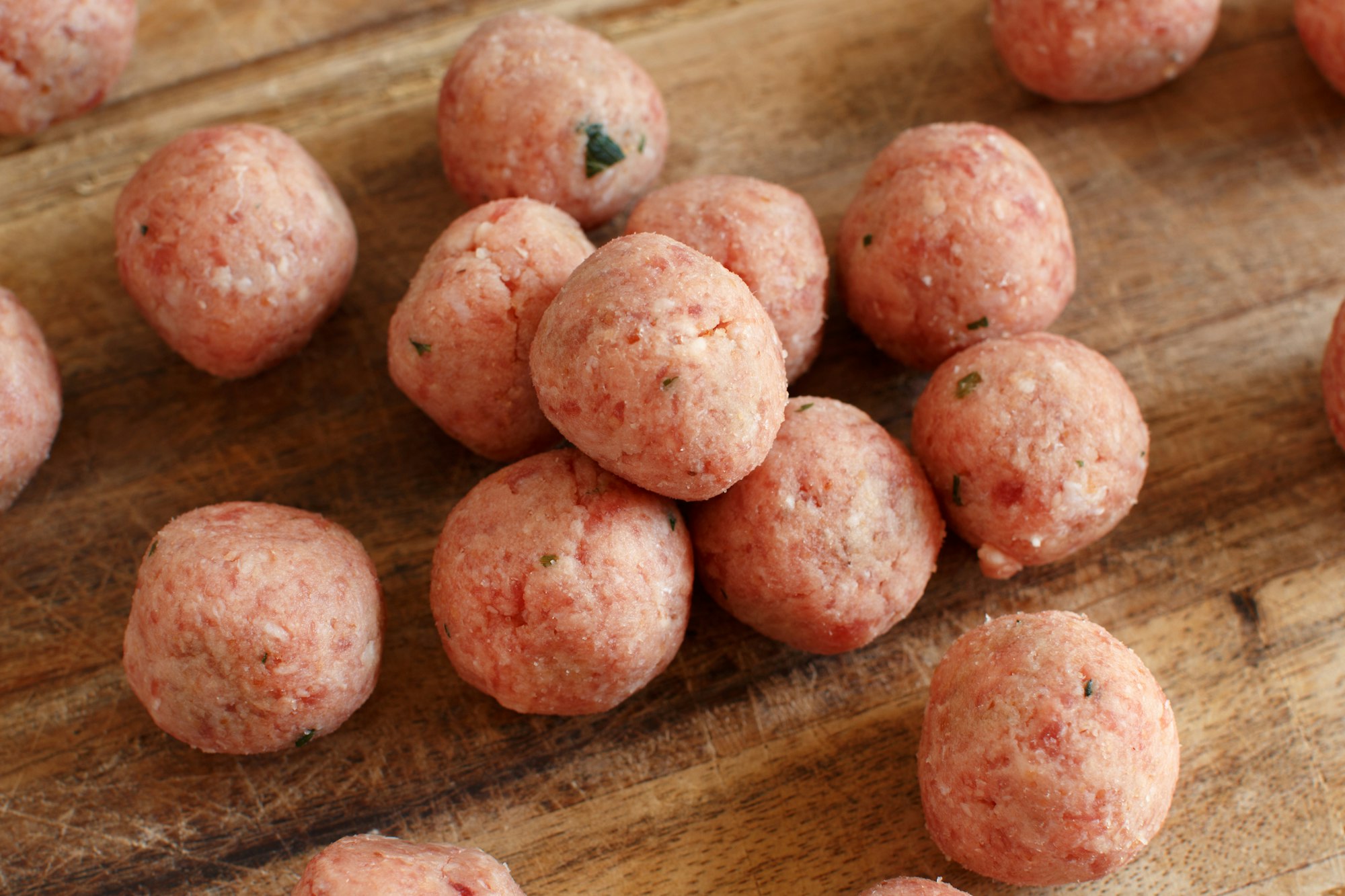 Raw meatballs ready to cook on a wooden board